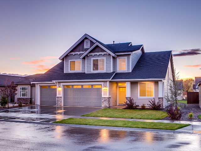 Two-story suburban home at dusk after rain, with a dark shingle roof