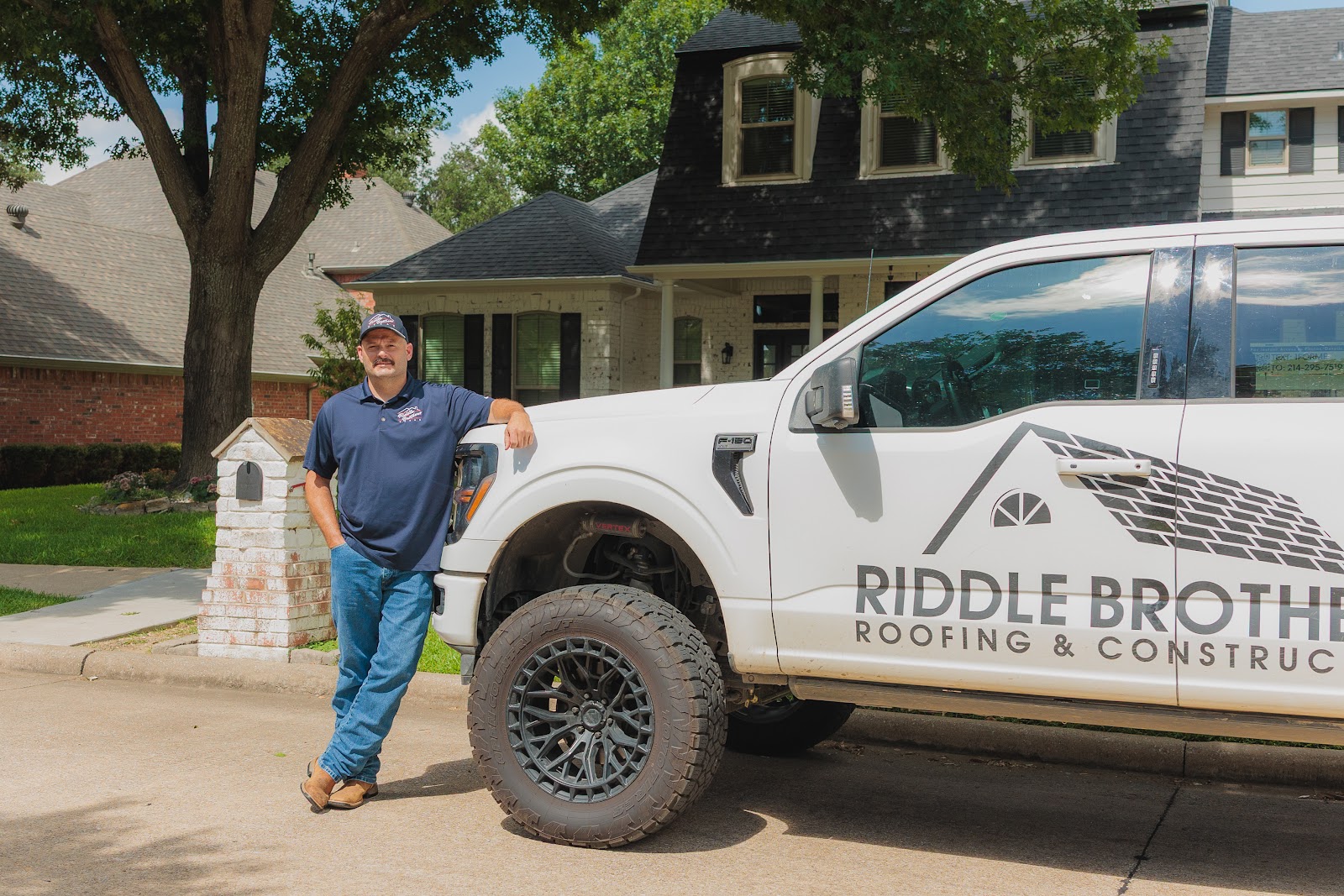 Brian from Riddle Brothers with a company truck in front of a completed roof replacement in North Texas (by Riddle Brothers Roofing & Construction)