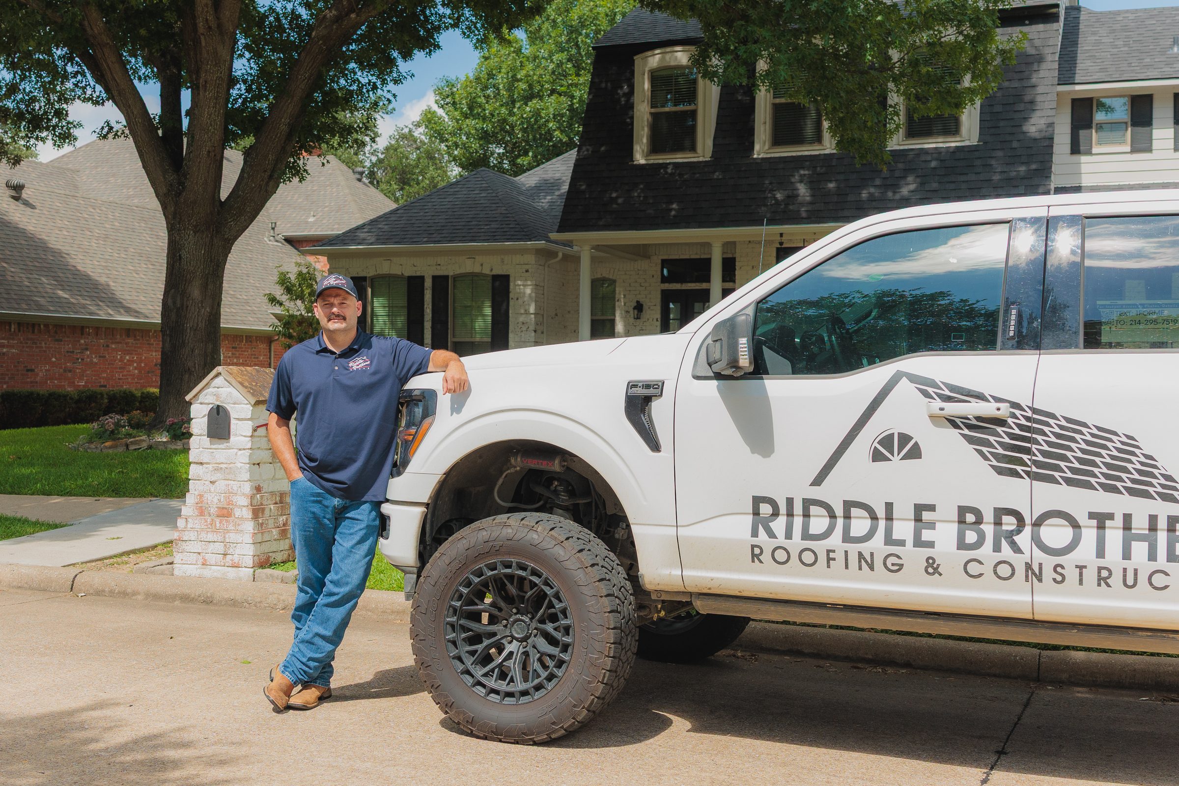 A Riddle Brothers team member beside a company truck outside a brick home